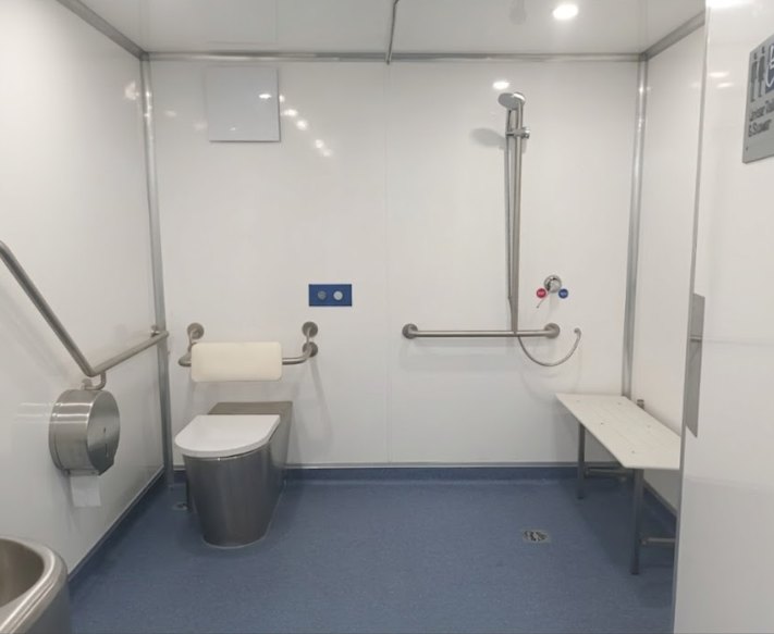 Accessible bathroom in the Mobile Access Facility with toilet, grab rails, shower rail and fold-down seat