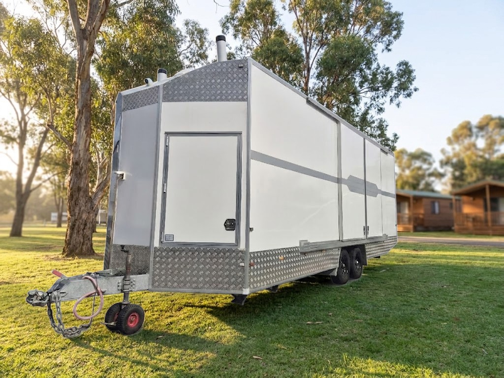 Mobile Access Facility™ on the grass at a holiday park beside cabins and gum trees, photograph of the unit with the setting illustrated