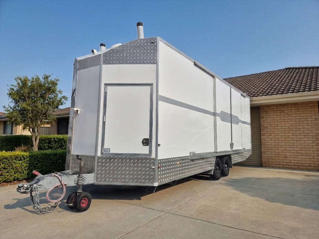 Mobile Access Facility™ parked on the driveway of a brick home, photograph of the unit with the setting illustrated